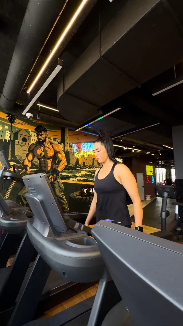 Une adhérente sur un tapis de course dans l’espace cardio